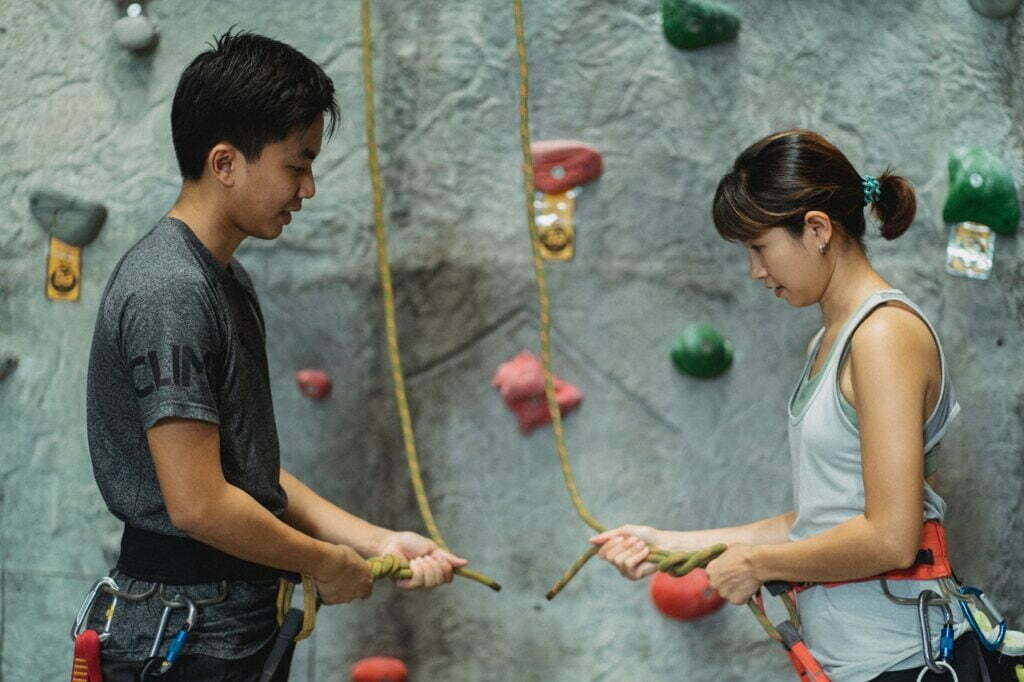 Two climbers are listening to one another and learning how to climb the wall.  They are aware that they can best achieve if they work together and do not let their ego control the situation.